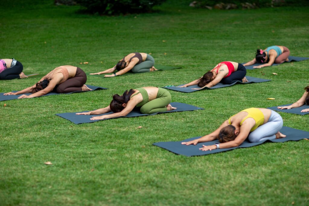 Yoga group people training and warrior pose attending yoga outside at park in sunset group of asian young women yoga exercising training in serene ocean scaled