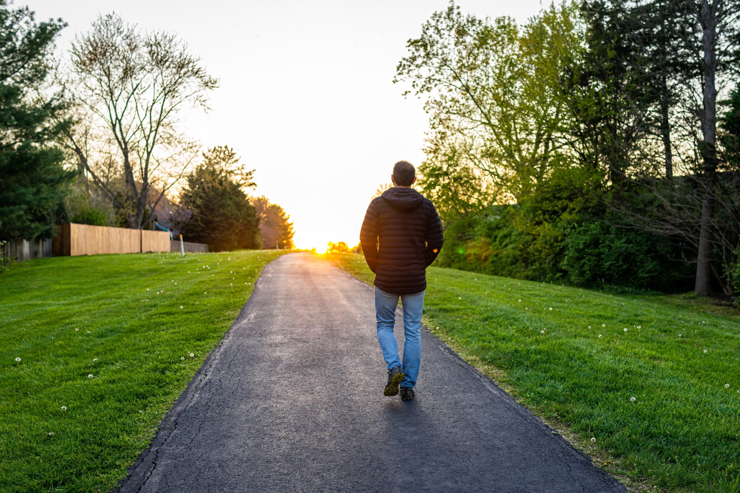A hopeful person walking toward sunlight on a nature trail or open road, symbolizing a fresh start and healing