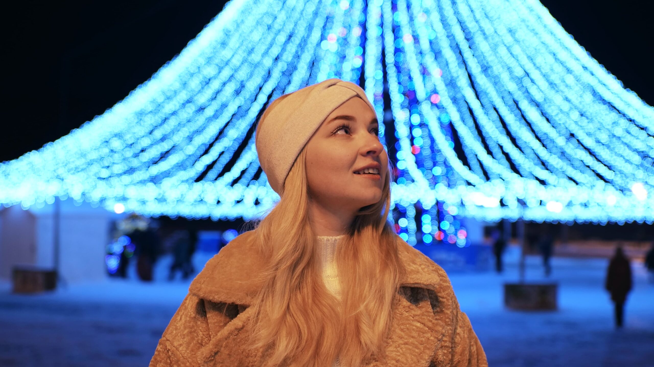 person walking peacefully through a park decorated with holiday lights