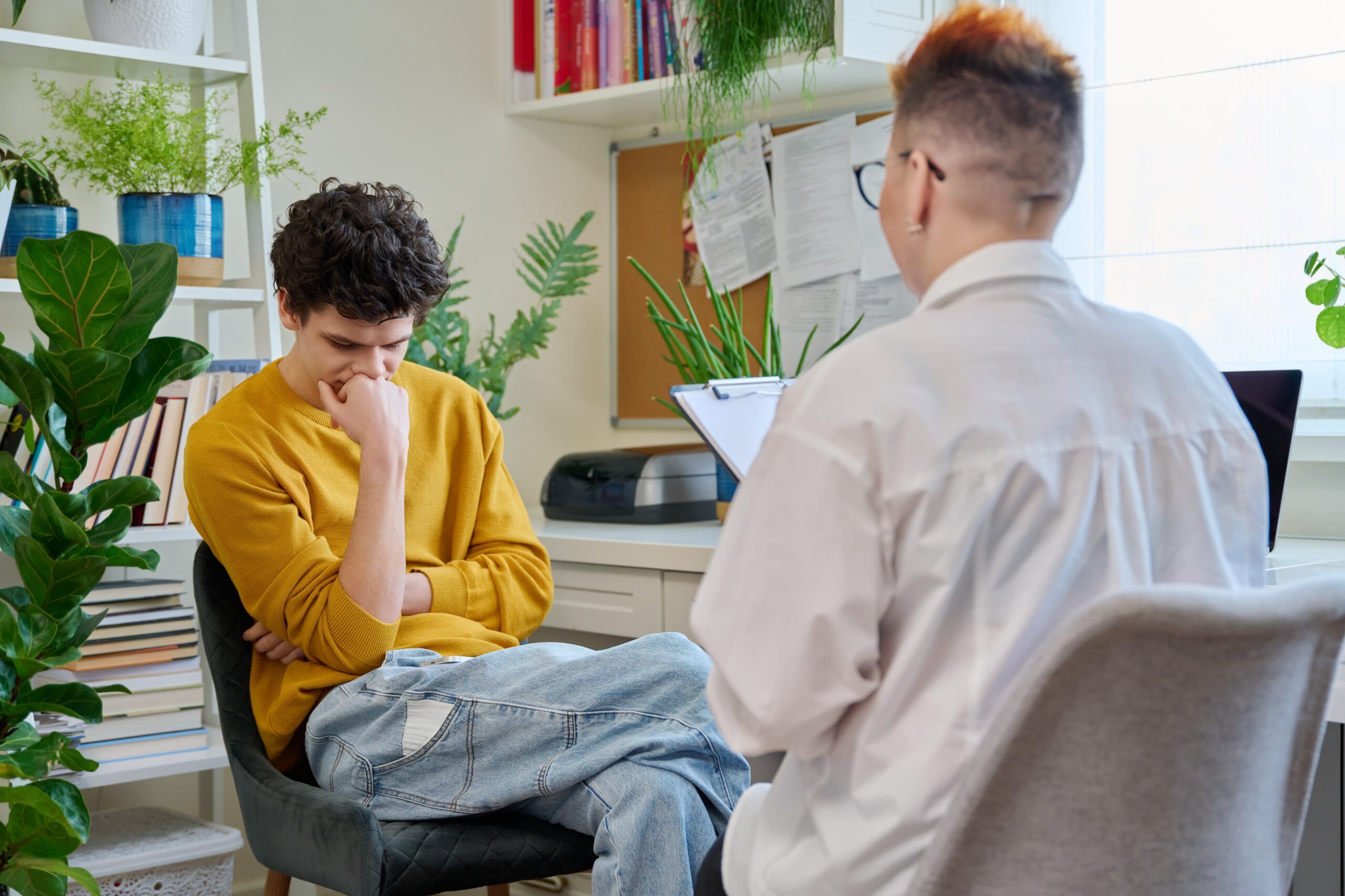 A young adult sitting with a counselor or mentor in a calm setting, having an open conversation Young adult talking with a counselor about mental health and addiction